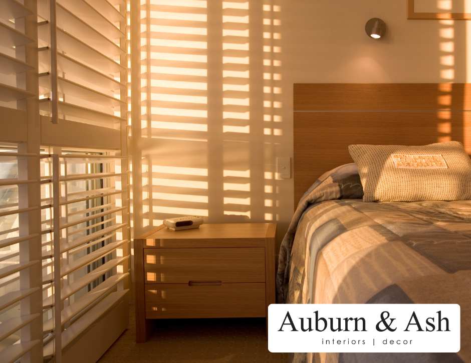 Light pours in through the horizontal blinds of a bedroom. Shop for window blinds in Red Deer at Auburn & Ash Design.